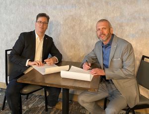 Matt Brewer and Paul Belair seated at a table signing a Memorandum of Understanding