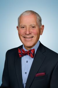Larry Masotti wearing a red and blue striped bow tie, a blue shirt and dark jacket